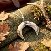 Hunting necklace with wild boar tusks and oak ornament in a forest setting