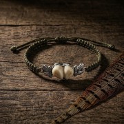 Srebrna bransoletka z grandlami leżąca na drewnianym starym stole